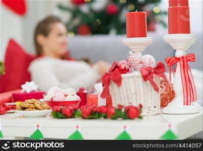 Closeup on table with Christmas decorations and female laying on couch in background