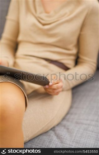 Closeup on tablet pc in hand of young woman sitting on divan