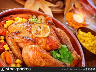 Closeup on tasty roasted chicken with vegetables on the table, traditional food of Thanksgiving day, autumnal holiday concept