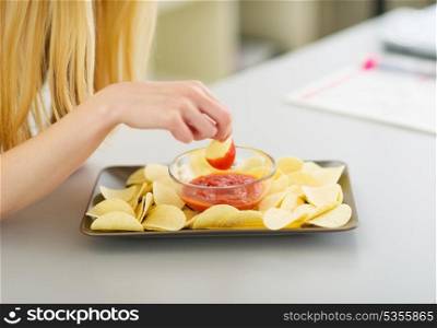 Closeup on teenage girl dunking chips in sauce