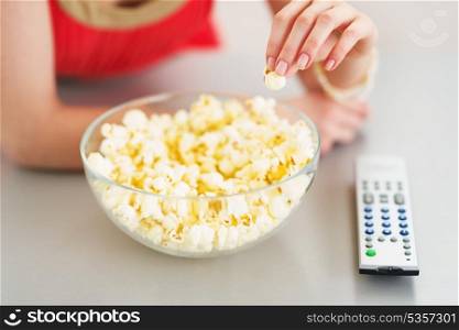 Closeup on teenager girl eating popcorn and watching tv