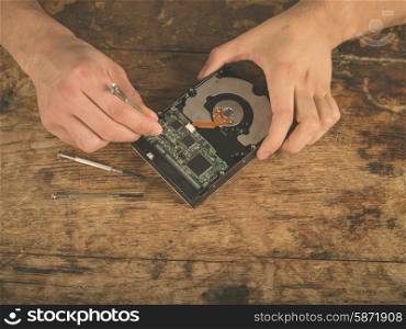 Closeup on the hands of a man fixing a harddrive at a desk