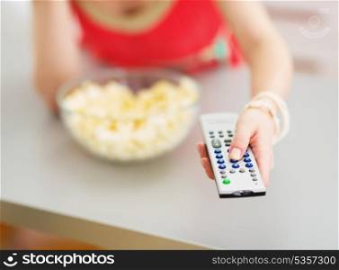 Closeup on tv remote control in hand of young woman