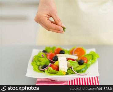 Closeup on woman adding fresh dill into salad