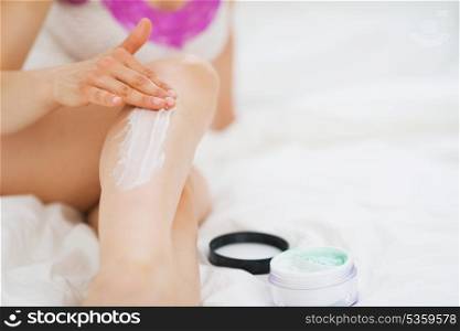 Closeup on woman applying creme on leg