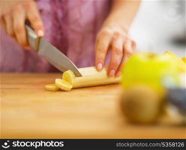 Closeup on woman cutting banana on cutting board