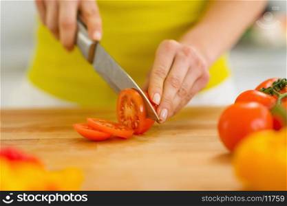 Closeup on woman cutting tomato