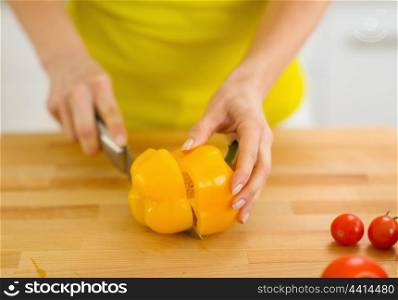 Closeup on woman cutting yellow bell pepper on cutting board