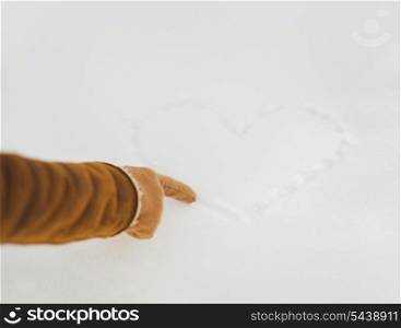 Closeup on woman hand drawing heart on snow