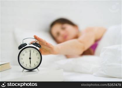 Closeup on woman hand reaching to turn off alarm clock