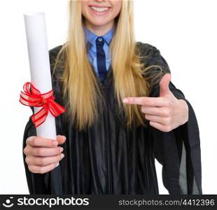Closeup on woman in graduation gown pointing on diploma