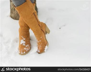 Closeup on woman legs in winter boots on snow