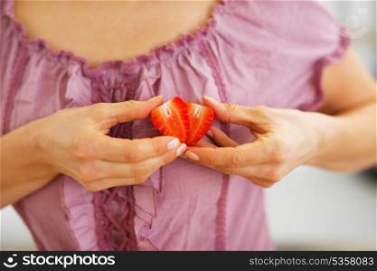 Closeup on woman making heart with strawberry slices
