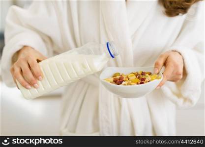 Closeup on woman pouring milk into plate with oatmeal