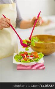 Closeup on woman putting fresh vegetable salad into plate
