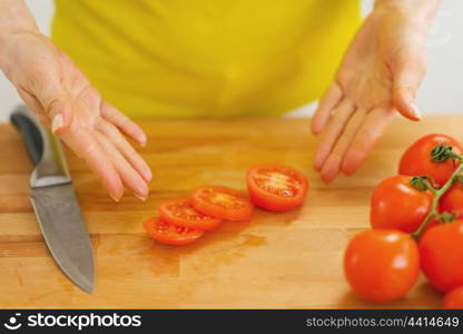 Closeup on woman showing slices of tomato on cutting board