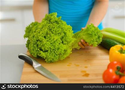 Closeup on woman tearing green salad on cutting board