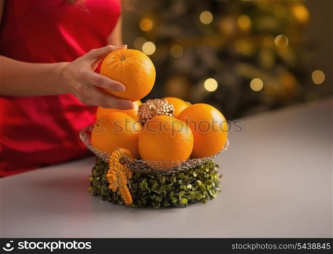 Closeup on young housewife decorating christmas plate with oranges