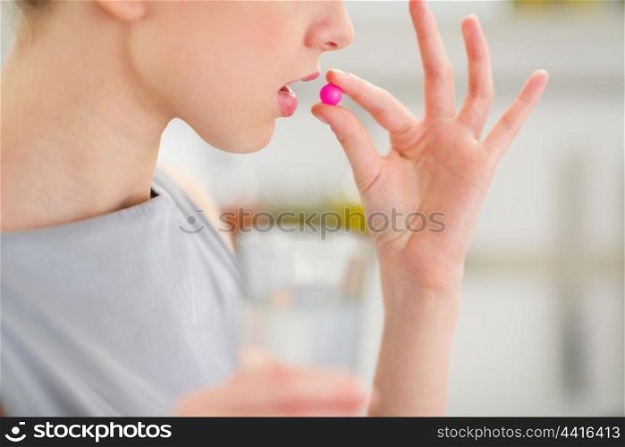 Closeup on young housewife eating pill