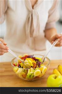Closeup on young housewife mixing fruits salad