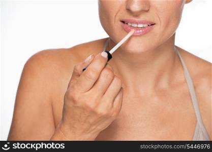 Closeup on young woman applying lip gloss