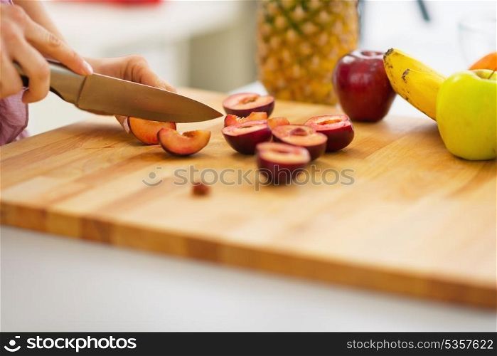 Closeup on young woman cutting plums