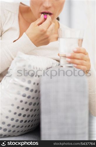 Closeup on young woman eating pill
