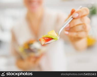 Closeup on young woman giving spoon with salad