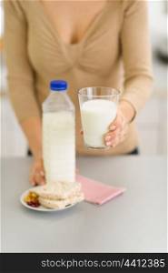 Closeup on young woman holding out glass of milk
