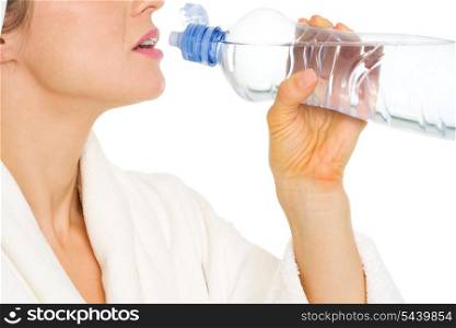 Closeup on young woman in bathrobe drinking water from bottle