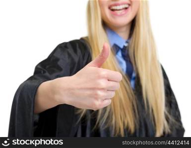 Closeup on young woman in graduation gown showing thumbs up