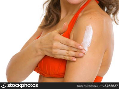 Closeup on young woman in swimsuit applying sun block creme