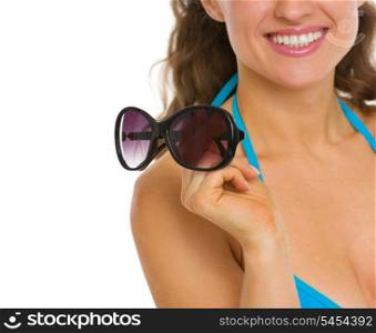 Closeup on young woman in swimsuit holding sunglasses