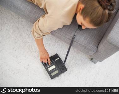 Closeup on young woman laying on couch and dialing phone number