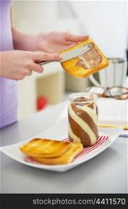 Closeup on young woman making toast with chocolate cream