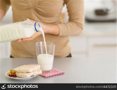 Closeup on young woman pouring milk into glass