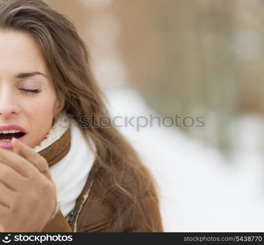 Closeup on young woman warming hands in winter park