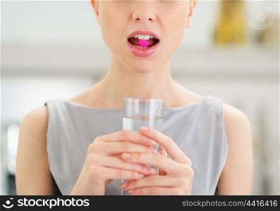 Closeup on young woman with pill in mouth