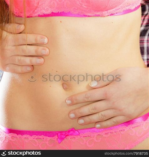 Closeup part of beauty female body, girl in pink lace lingerie. Fit and slim young woman belly with hands on it