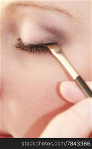 Closeup part of face female eye, woman applying makeup on eyes with brush
