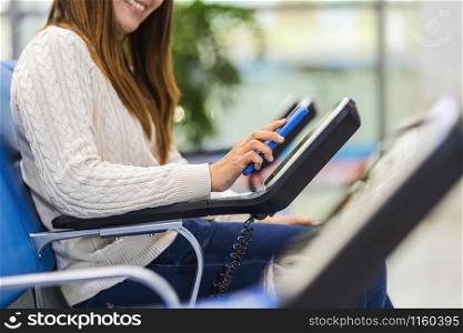 Closeup passenger hand holding and scanning mobile phone with qr code scanner machine of message chair in airport, Technology with travel and tourist, check-in self service,transportation concept,