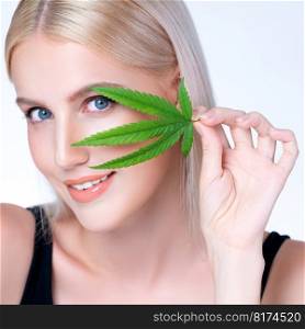 Closeup personable beautiful white blond hair with perfect smooth makeup skin hold cannabis green hemp in isolated background for natural CBD skincare treatment with perfect facial gesture expression.. Closeup personable blond hair woman holding CBD leaf in isolated background.