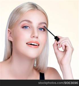 Closeup personable woman with blond hair putting black mascara with brush in hand on long thick eyelash. Perfect fashionable cosmetic clean facial skin with beautiful eye young woman.. Closeup personable beautiful woman putting alluring black mascara eyelashes.