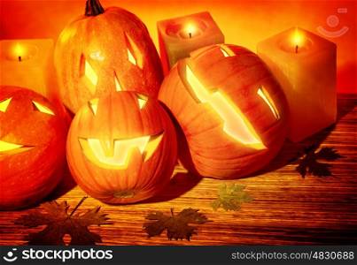 Closeup photo of a carved pumpkins with scary faces and glowing candles on the table, festive party decoration for Halloween holiday