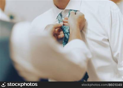 Closeup Photo of a Groomsman Tying the Groom’s Tie. Happy Wedding Day. Preparation for the Biggest Day in Life.. Groom with Best Man