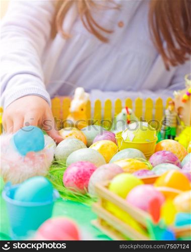 Closeup photo of a little girl&rsquo;s hand painting many colorful eggs, traditional Easter symbol, the winner of the eggs hunt, happy religious holiday