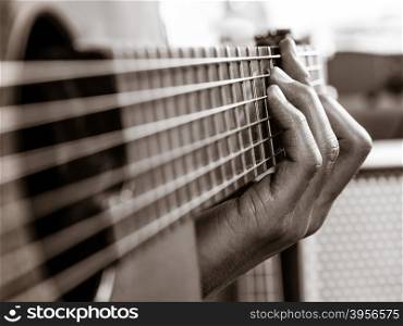 Closeup photo of a man playing his acoustic guitar. Focus on the fingers.&#xA;