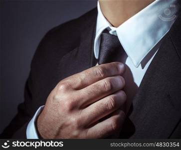 Closeup photo of a man wearing stylish black suit and tie over dark background, body part, mens fashion concept