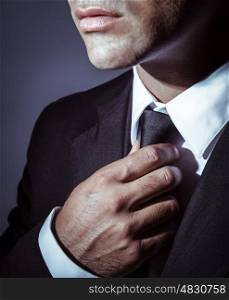 Closeup photo of a serious businessman wearing stylish black suit and tie over dark background, face part, mens wear fashion concept