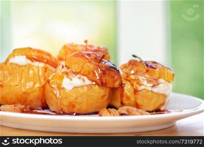 Closeup photo of a tasty baked apples stuffed with cheese cream, flavored with cinnamon, nuts and honey, served on the white plate, healthy nutrition, delicious fruit dessert